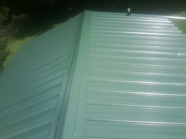 New green metal panels meeting at the ridge of a roof — Flat Roof Repair work by our crew in Mount Ephraim