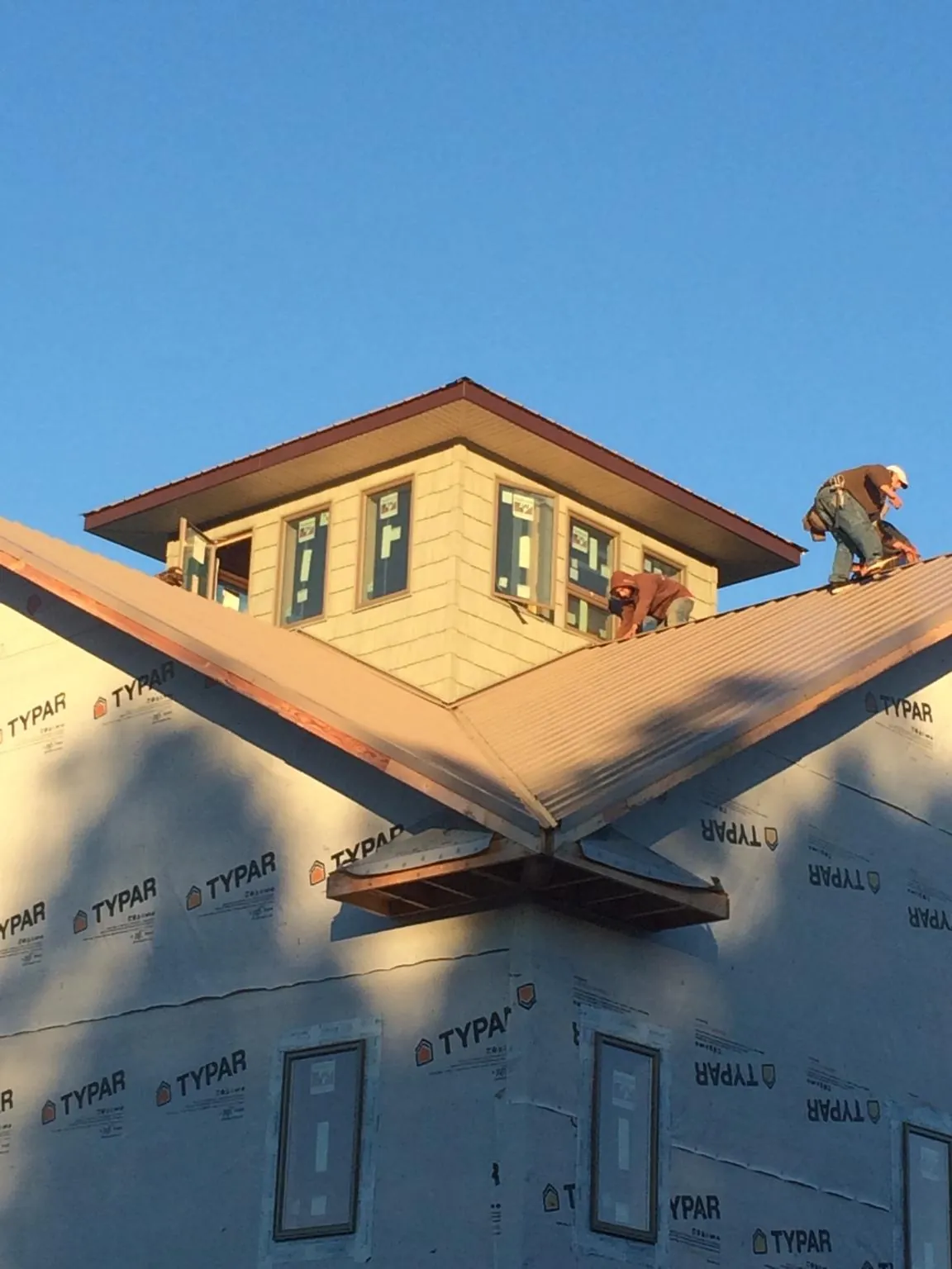 Roofers working around a rooftop cupola on a new metal roof at sunset — Roof Waterproofing in Mount Ephraim by Roofing Brothers